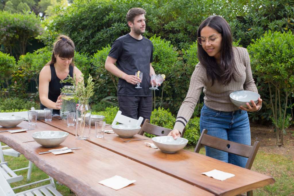 positive-people-serving-table-with-plates-outdoors