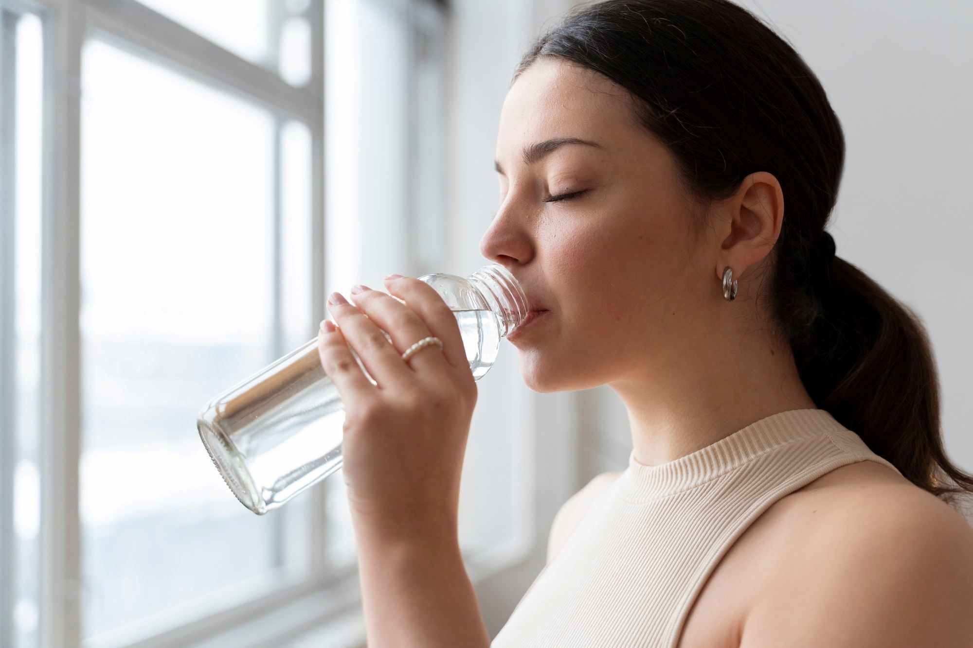 Woman drinking water to achieve youthful glow