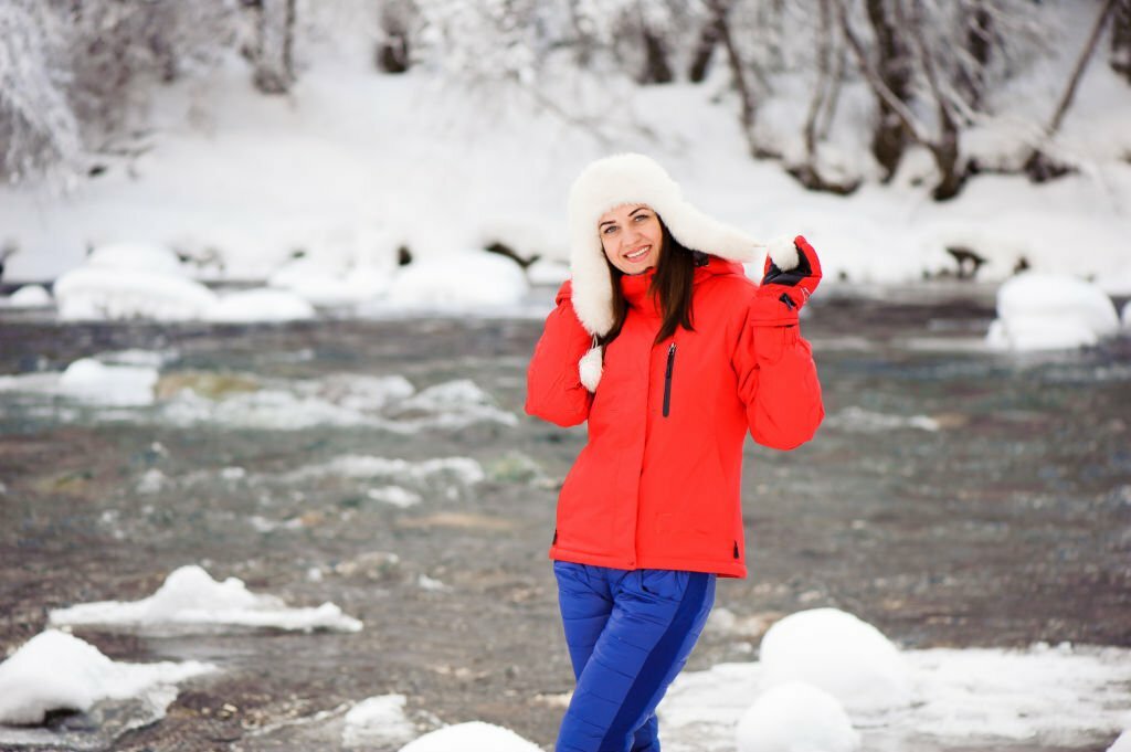 Young beautiful girl in the winter forest near the river.